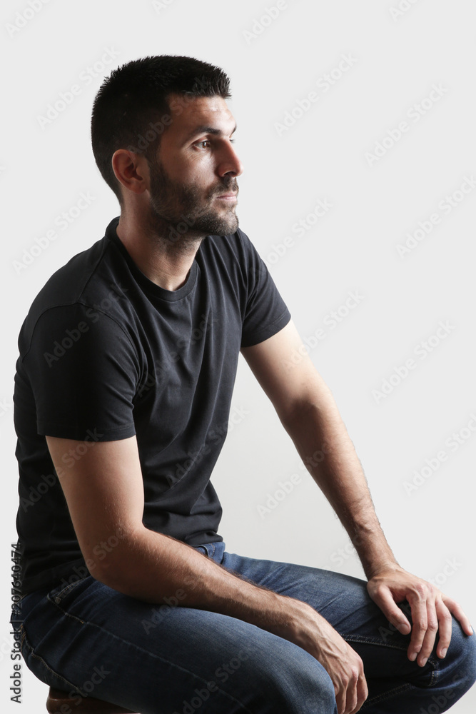 Portrait of young man sitting, studio shot on the grey background Portrait of young man sitting, studio shot on the grey background