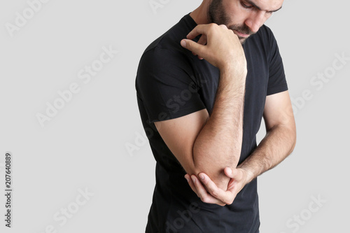 Acute elbow pain. Man holds hand on his pain elbow.