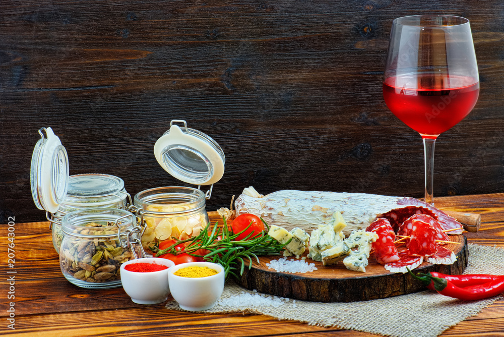 Sliced cured sausage with spices and a glass of red wine.