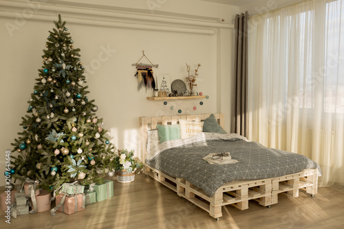 new year's bedroom interior. tree by the bed. bed with grey blanket. bedroom interior