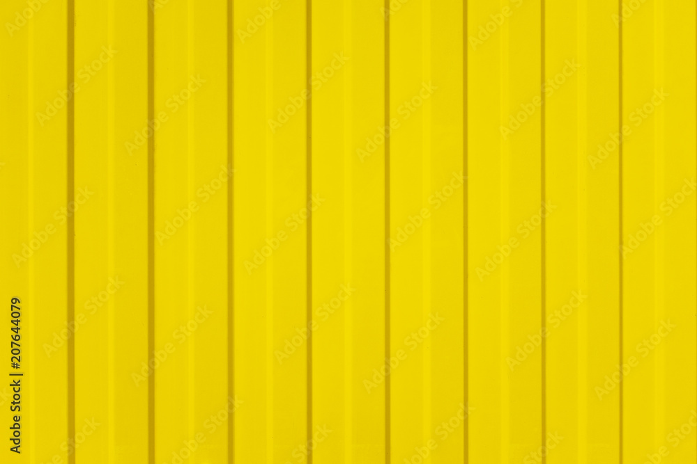 A corrugated fence of yellow metal sheets with screw. Texture of metal