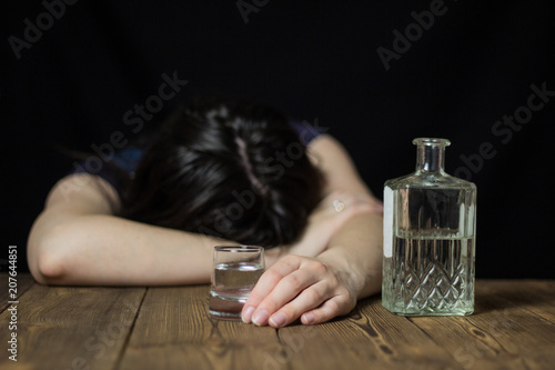Konstfotografi A drunk girl laid her head on a table, in her hand a glass of alcohol and a bott