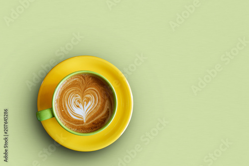 Colorful cup of coffee on a light green background. Top view. Copyspace.