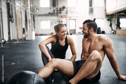 Two people sitting on a gym floor after working out