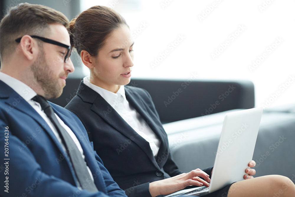 Young businesswoman and her colleague looking through online financial data or statistics Young businesswoman and her colleague looking through online financial data or statistics