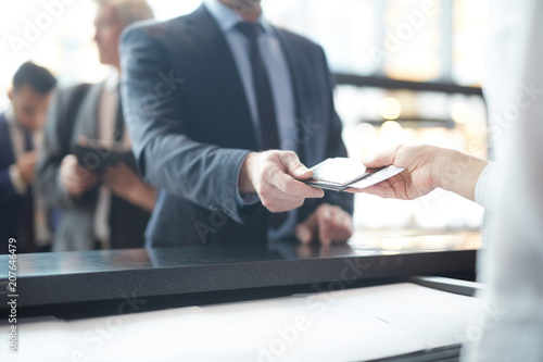Foto Hand of passenger giving his documents dor check-in to manager by counter