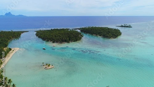 Aerial view of Motu Tautau, palm trees on little islets and turquoise crystal clear water of blue lagoon, tropical paradise of South Pacific Ocean - Tahaa island, landscape of French Polynesia photo