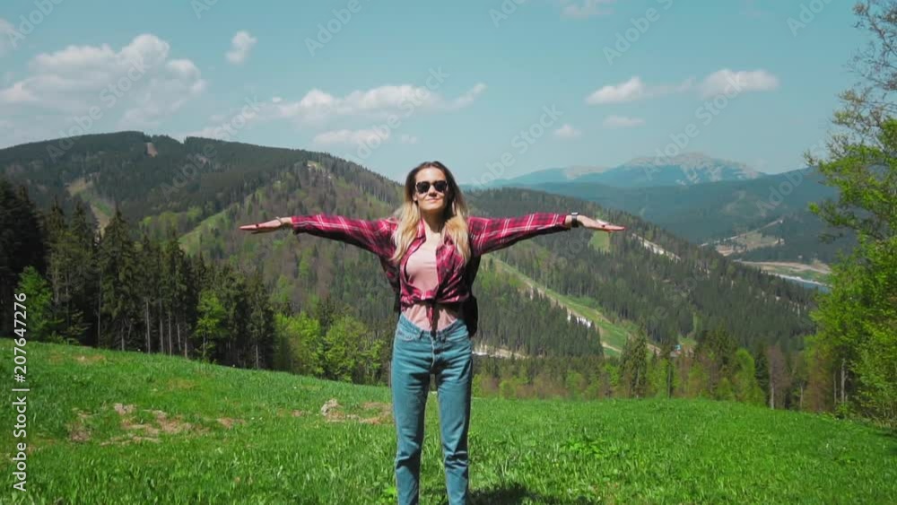 A young Caucasian woman with a backpack and sunglasses stands on top of the mountain and raises her hands. The concept of personal growth, overcoming difficulties in business, motivation of the A young Caucasian woman with a backpack and sunglasses stands on top of the mountain and raises her hands. The concept of personal growth, overcoming difficulties in business, motivation of the