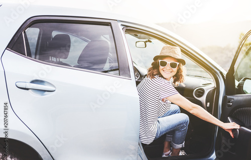 Young beautiful female travel girl in hat and sunglasses speaks by mobile phone on the background of her car while traveling in the mountains, renting and car service © olezzo