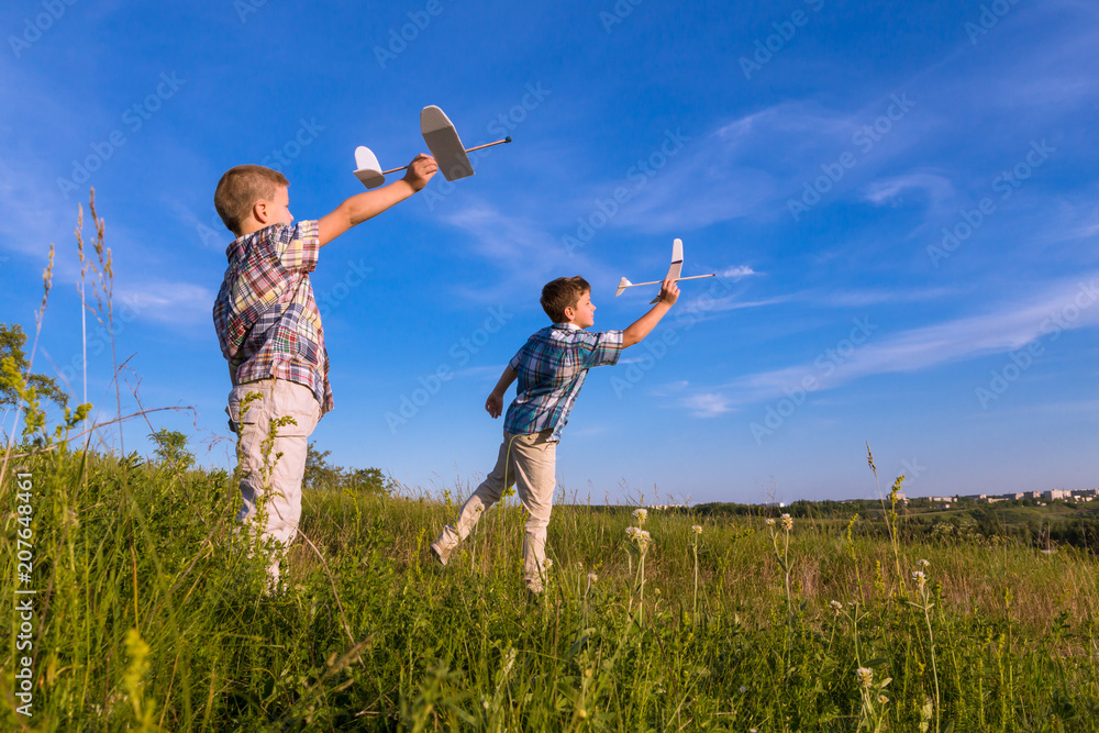 Two kids launch his airplans at field Two kids launch his airplans at field