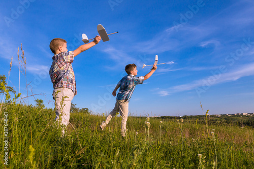 Two kids launch his airplans at field