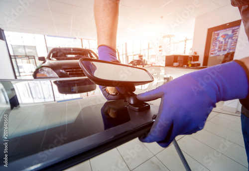 Automobile special workers replacing windscreen or windshield of a car in auto service station garage. photo