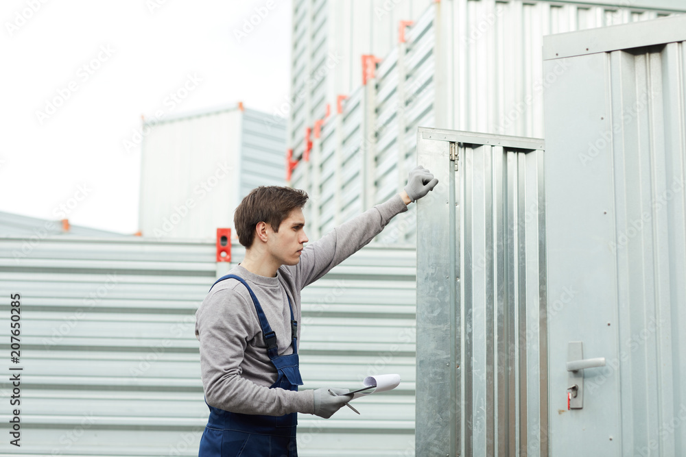 Worker with documents looking at cargo inside storage container during revision Worker with documents looking at cargo inside storage container during revision