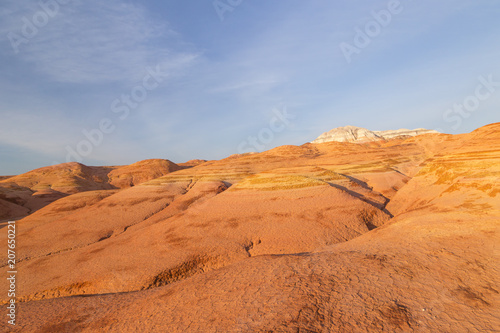 Multicolored red, orange and yellow striped hills under a bright blue sky in Eastern Kazakhstan