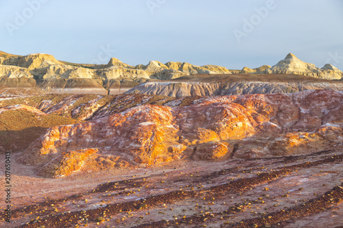 Multicolored red, orange and yellow soil with with fragments of saline soil and lichen under a bright blue sky in Eastern Kazakhstan