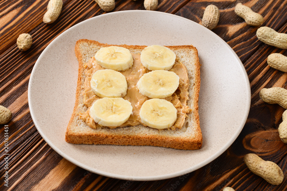 Peanut butter toast with banana slices on wooden background Peanut butter toast with banana slices on wooden background