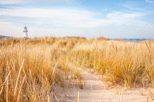 Lighthouse visible above the dune grasses on a beach photo