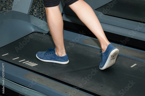Legs of sportsman woman running on a treadmill: sport and healthy lifestyle concept. Legs of an athlete in sneakers keds closeup