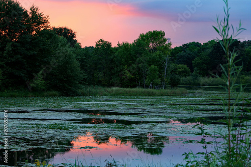 McDonough Lake in Eagan, Minnesota at sunset with a colorful pink sky and reflecting off of the water.
