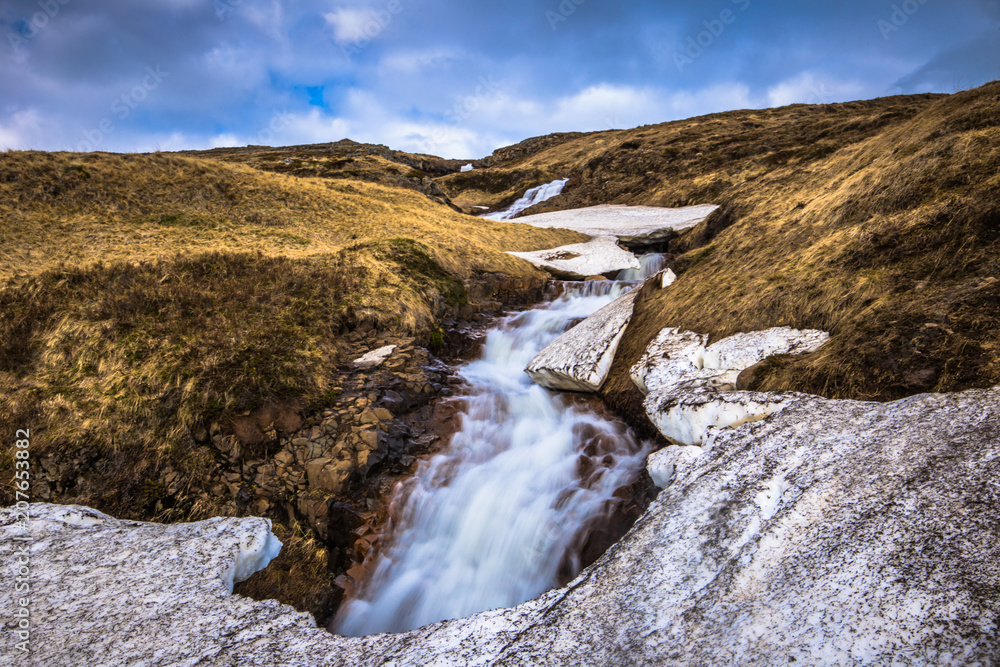 Icelandic wilderness - May 08, 2018: Small waterfall in the icy wilderness of Iceland Icelandic wilderness - May 08, 2018: Small waterfall in the icy wilderness of Iceland