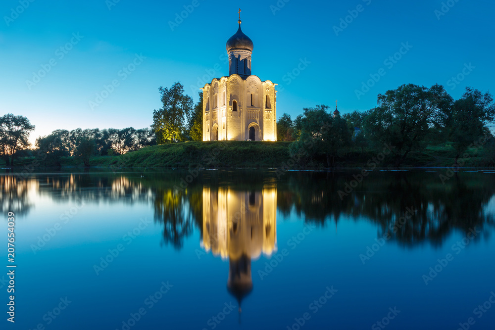 Night view of the Church of the Intercession on the Nerl with a reflection in the water.
