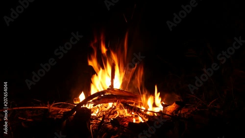 Video footage of a burning and sparking campfire at night with burning woods in 4K resolution.