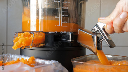 Slow juicer is making fresh carrot and orange juice. photo