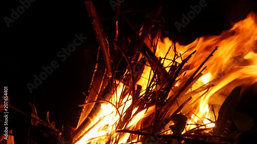 Video footage of a burning and sparking campfire at night with burning woods in 4K resolution.