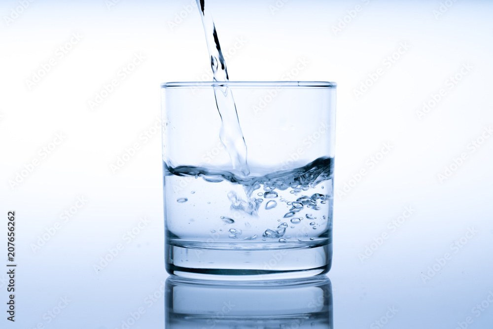 Glass of water with pouring from the bottle, studio shot Glass of water with pouring from the bottle, studio shot
