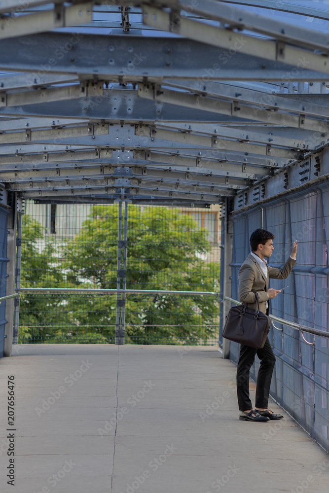 Fototapeta premium A man in a suit is standing on a bridge looking out into the distance