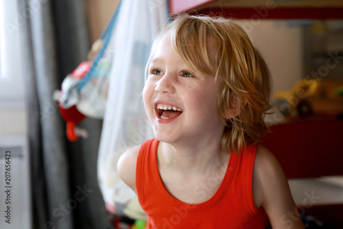 Photos Petit garçon blond heureux rigole en regardant la télé