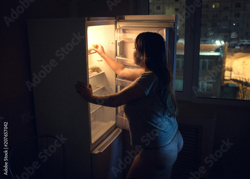 Cuadro en lienzo Sexy chubby woman craving and looking for food in a frige late at night