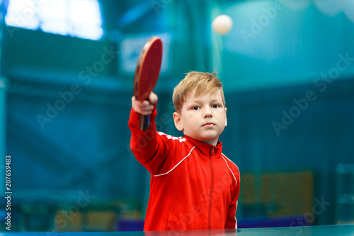 child plays table tennis in the gym, hit the ball with racket