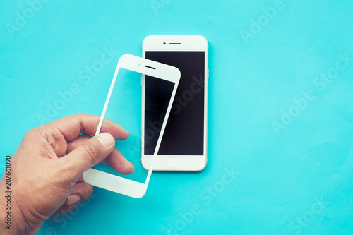 Fotografija Male hand stick tempered glass shield or film screen cover with mobile phone