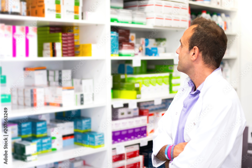 Adult man pharmacist in pharmacy looking for medications Adult man pharmacist in pharmacy looking for medications