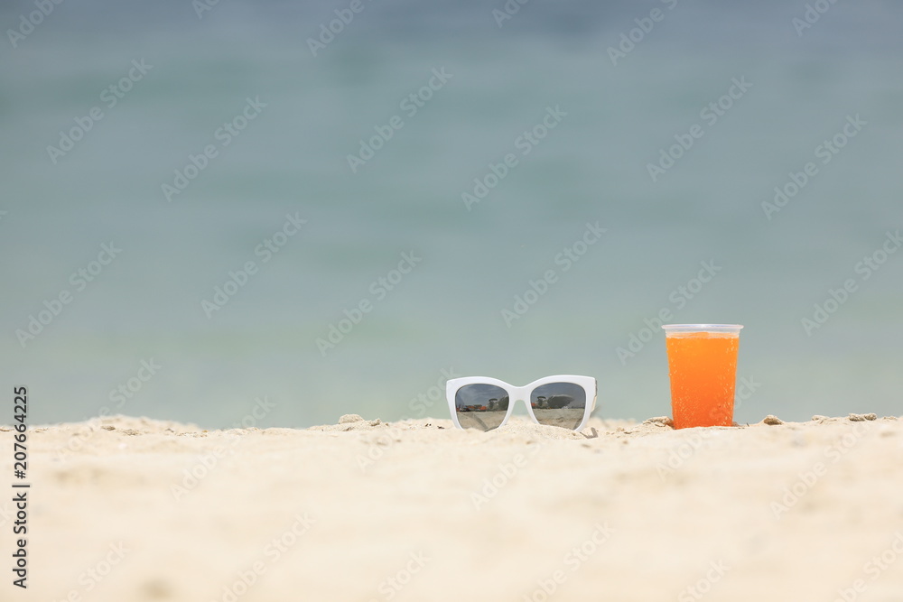 summer background, sunglasses and drink on the beach sand