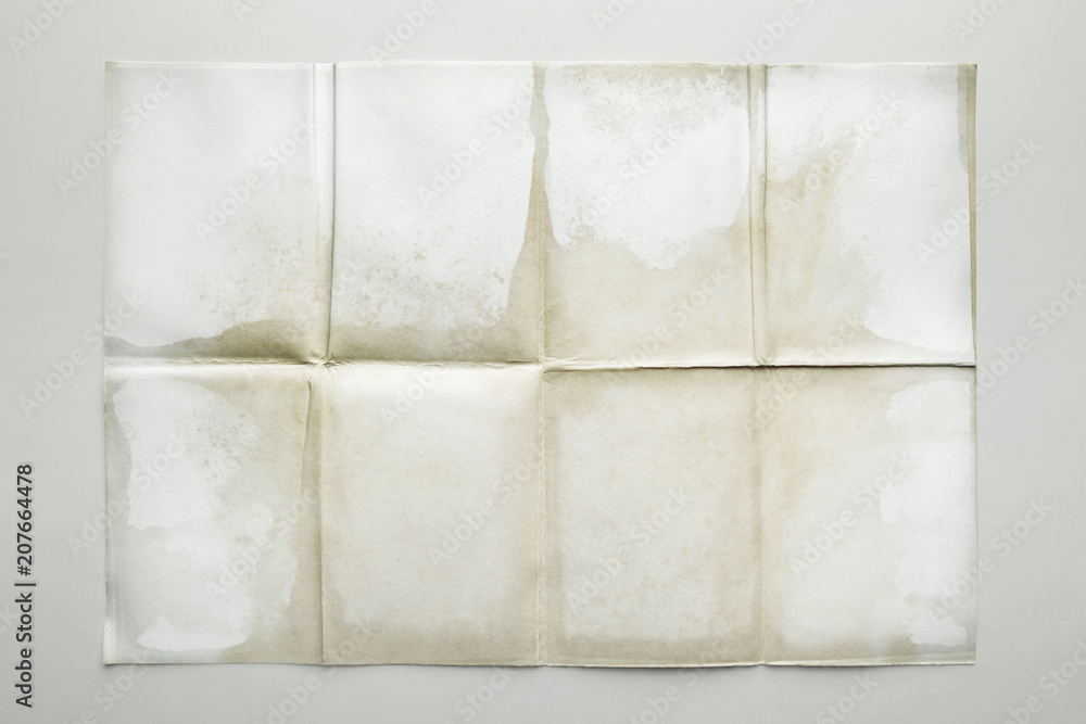 Empty sheet folded in eight, old paper isolated on gray background