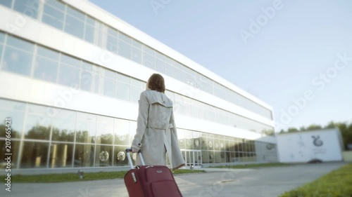 A woman with a suitcase heading to the airport building. photo