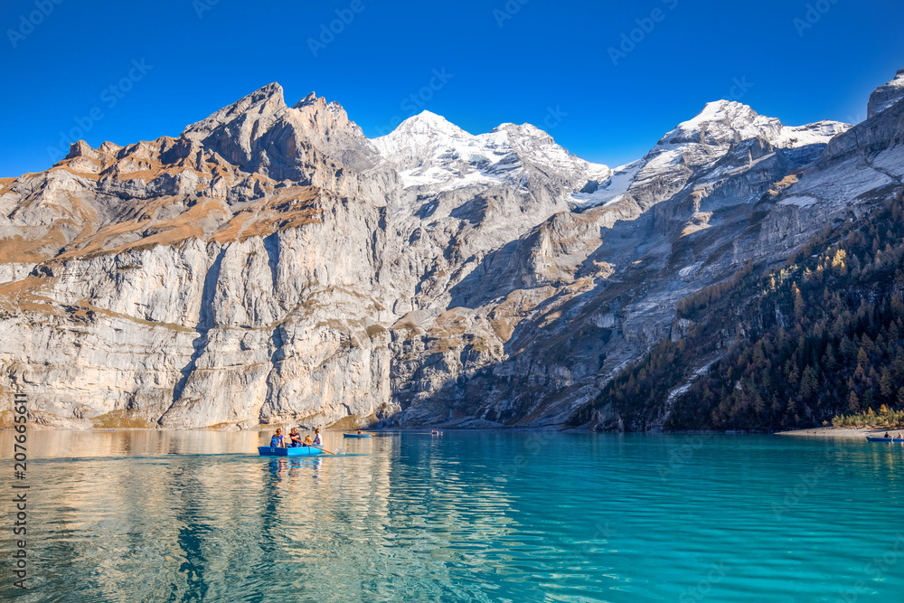 Amazing tourquise Oeschinnensee lake with waterfalls, wooden chalet and Swiss Alps, Berner Oberland, Switzerland