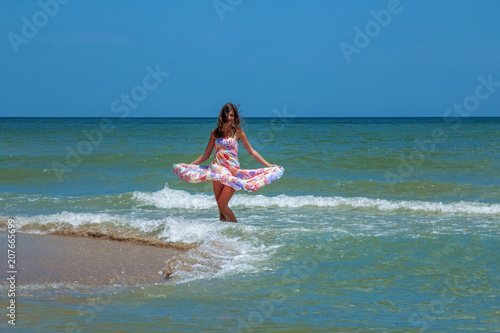 Young beautiful woman dancing in water of sea as symbol of freedom and happiness.