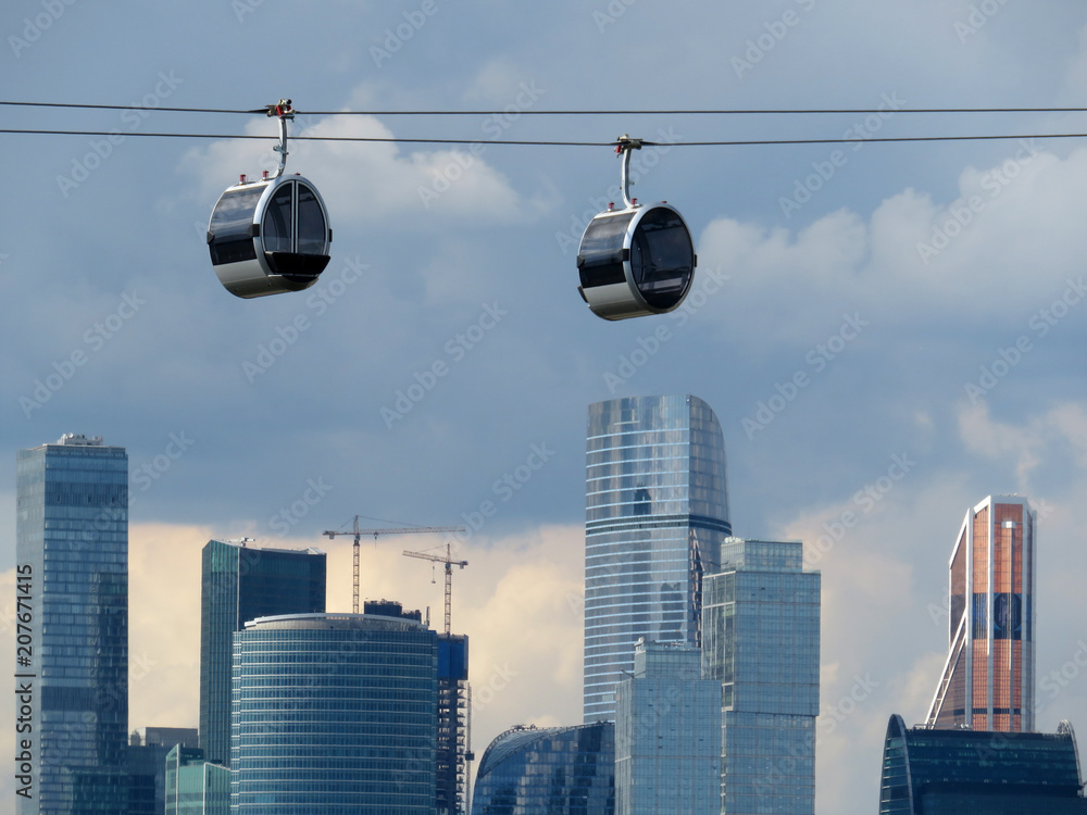 New cable car cabins in the Luzhniki against skyscrapers of Moscow-city in Russia - obrazy, fototapety, plakaty 