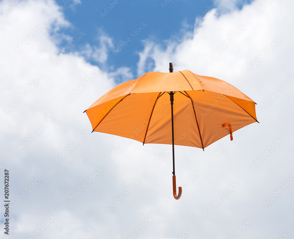 Opened umbrella orange color in blue sky and white cloud background, Street decoration.