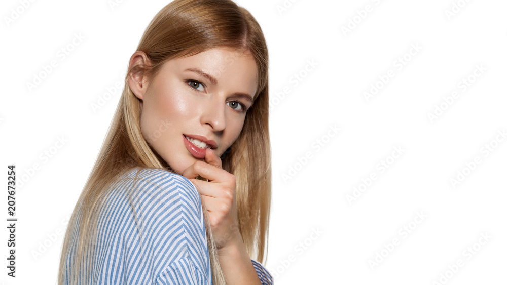 Waist up portrait of beautiful girl in striped shirt posing at studio. Alluring female with long hair and natural make-up. Isolated on light blue background Waist up portrait of beautiful girl in striped shirt posing at studio. Alluring female with long hair and natural make-up. Isolated on light blue background