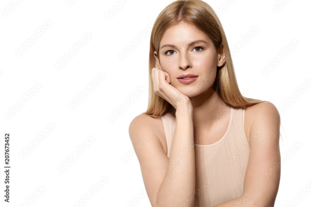 Waist up portrait of attractive sensitive woman in fashionable dress with natural hairstyle and delicate make-up. She is standing and leaning on hand. Copy space. Isolated on light blue background Waist up portrait of attractive sensitive woman in fashionable dress with natural hairstyle and delicate make-up. She is standing and leaning on hand. Copy space. Isolated on light blue background