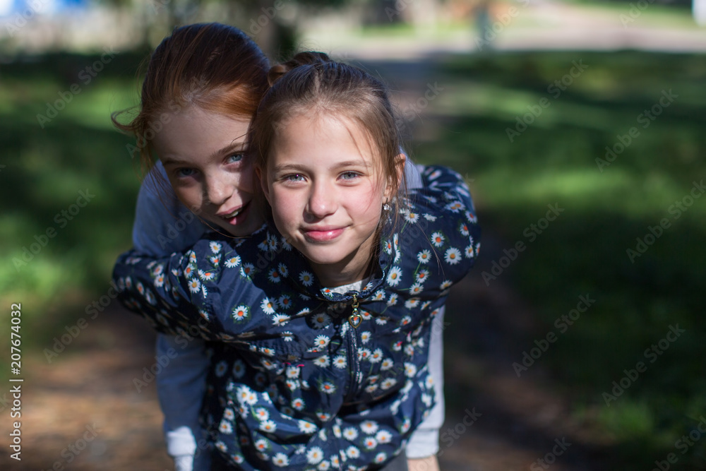 Fototapeta premium Two girls sisters or girlfriends having fun outdoors. Looking into the camera.