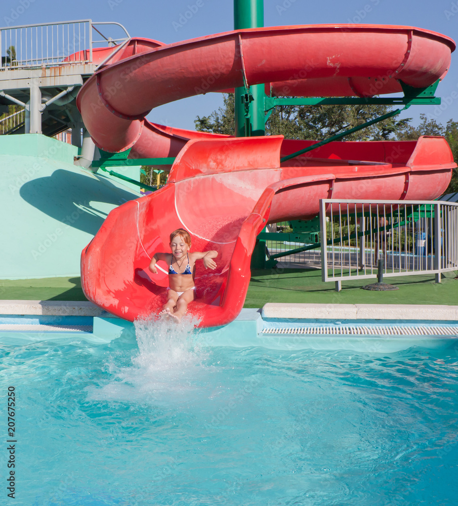 Beautiful red-haired child on a slide in the water Park.