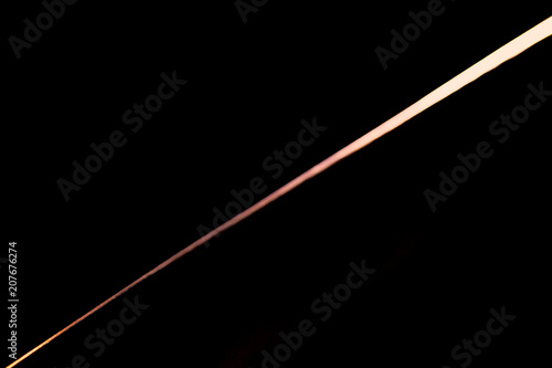 Narrow beam of light on the blade of a steel knife on a black abstract background