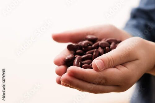 Small hungry child gets food donate help a volunteer  hands full of beans