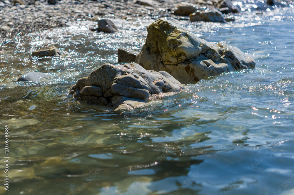 rocky sea shore with pebble beach, waves with foam rocky sea shore with pebble beach, waves with foam