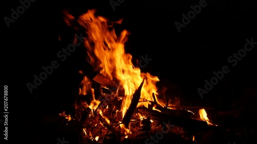 Video footage of a burning and sparking campfire at night with burning woods in 4K resolution.